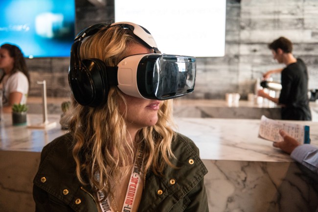 A young blonde woman wearing a virtual reality headset in a professional space, like she's testing it.